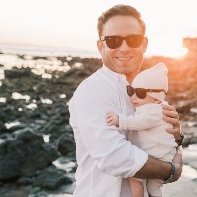 Zandy Reich is holding the baby as both are wearing shades.